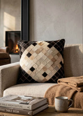Black and ivory cowhide patchwork cushion with diamond design styled on a neutral armchair