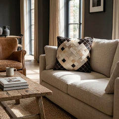 Black and ivory diamond cowhide cushion styled on a cream sofa in a warm contemporary interior