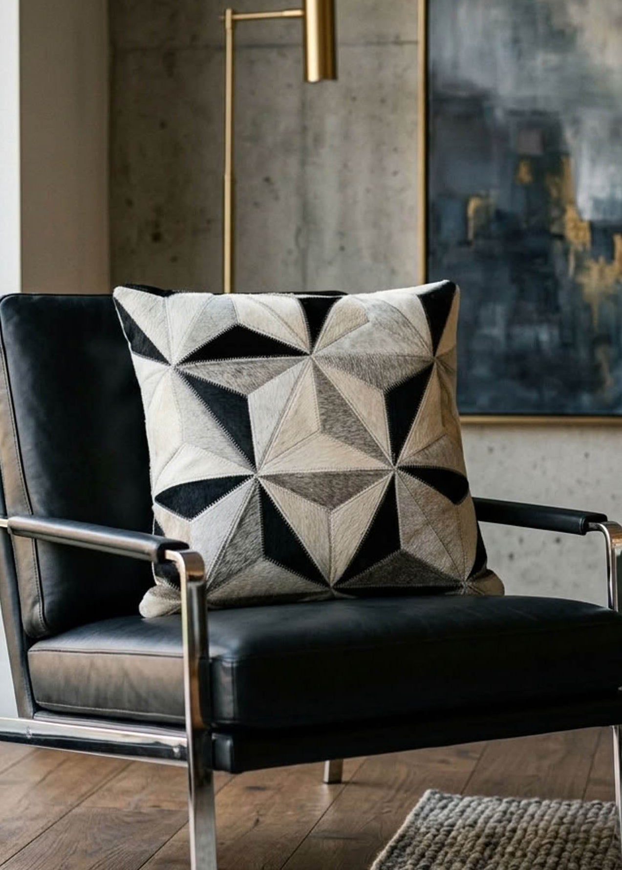 Black and ivory faceted cowhide cushion styled on a black leather armchair