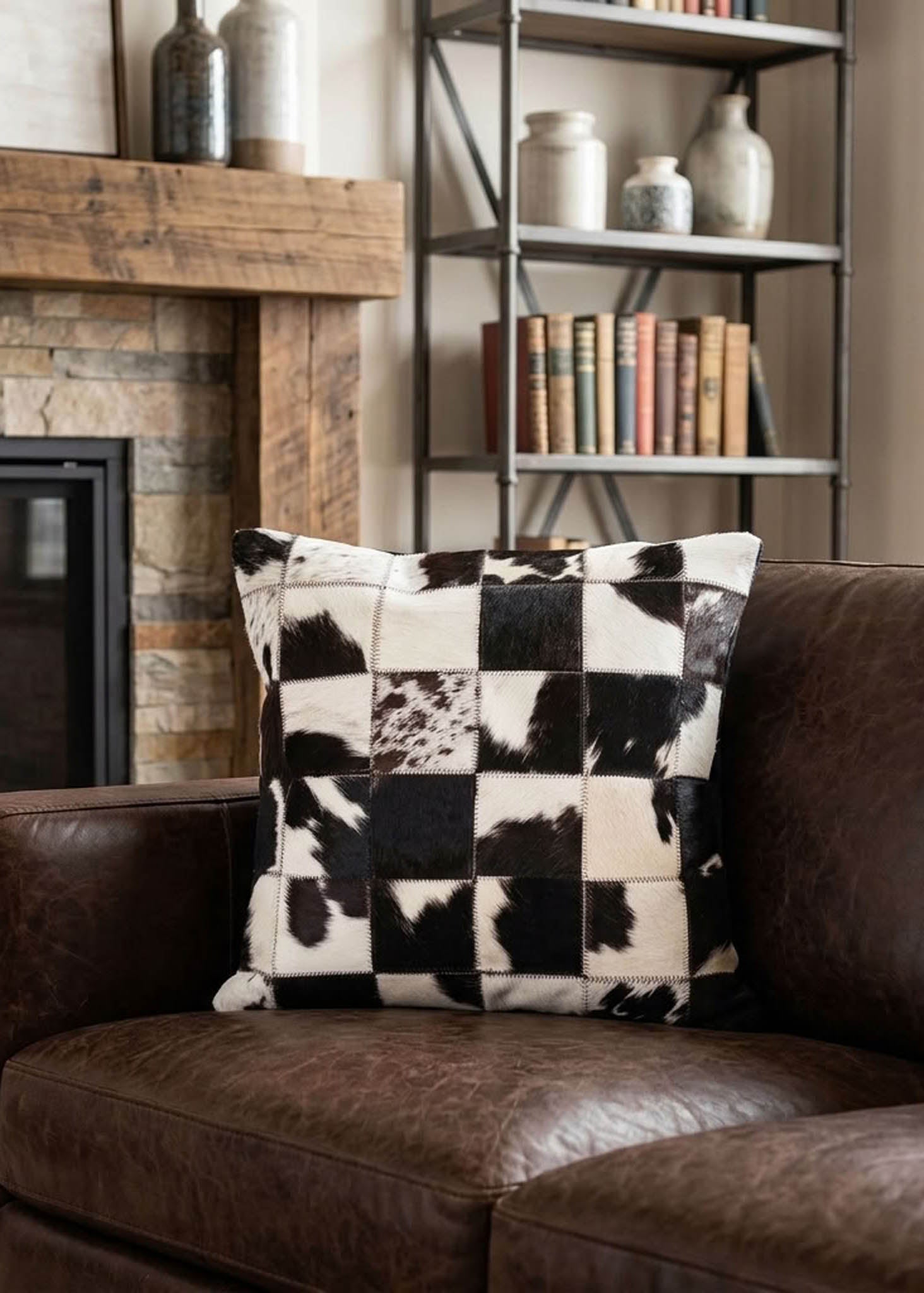 Black and white checkered cowhide patchwork cushion styled on a brown leather sofa