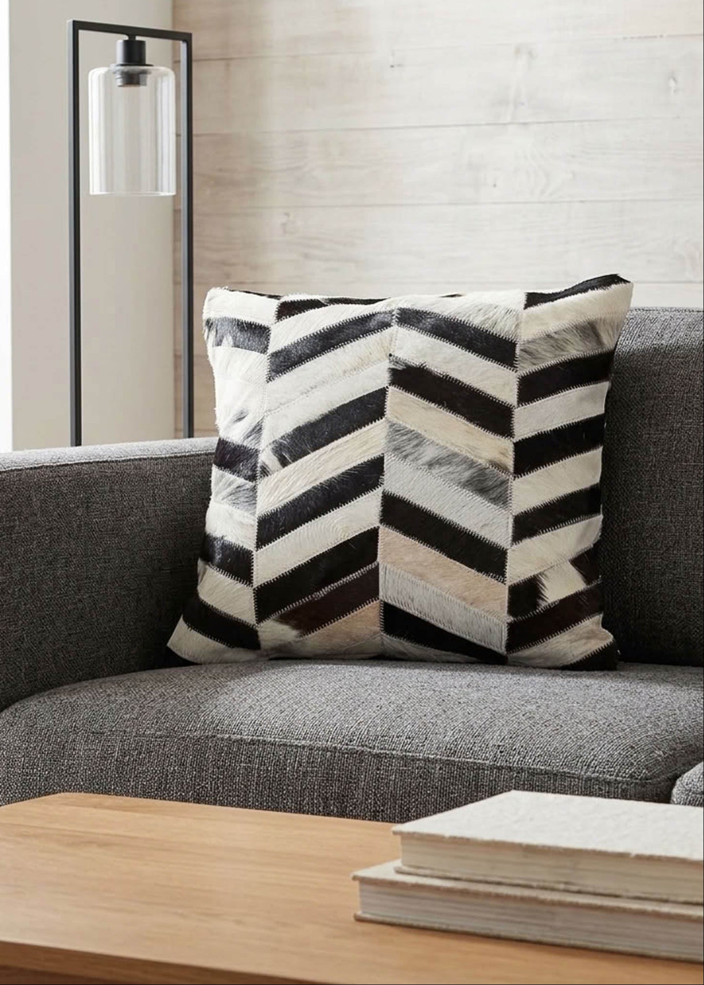 Black and white chevron cowhide patchwork cushion styled on a grey sofa in a modern living room
