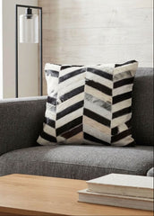 Black and white chevron cowhide patchwork cushion styled on a grey sofa in a modern living room