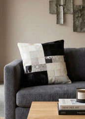 Black and white colour block cowhide patchwork cushion styled on a modern grey sofa