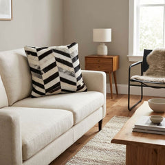 Black and white cowhide patchwork cushion with chevron design styled on a cream sofa