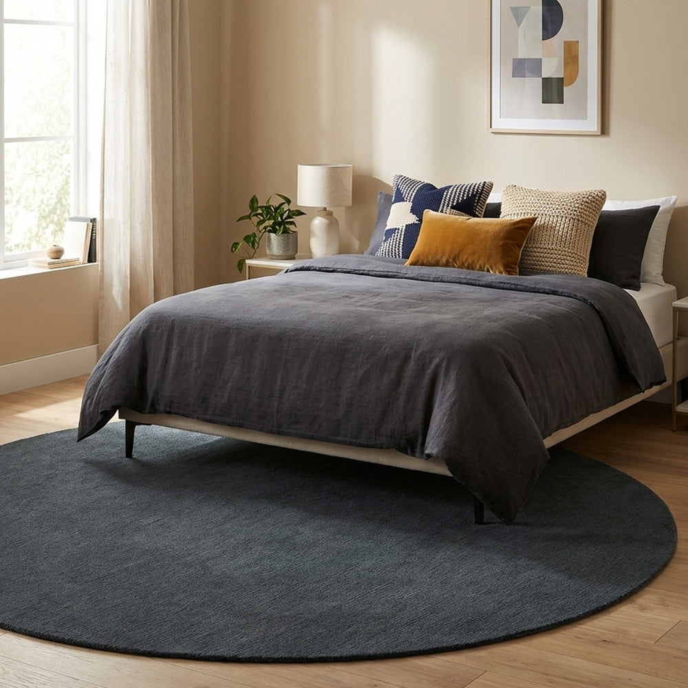Dark grey round wool rug in bedroom