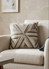 Ivory and grey radiant cowhide cushion styled on a cream armchair in a neutral contemporary interior