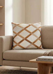 Tan and ivory lattice cowhide cushion styled on a beige sofa in a modern neutral interior