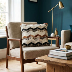 Tricolor cowhide patchwork cushion with chevron pattern on a neutral armchair in a modern living room