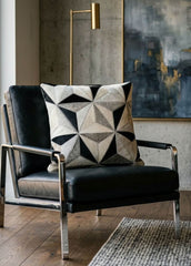 Black and ivory faceted cowhide cushion styled on a black leather armchair