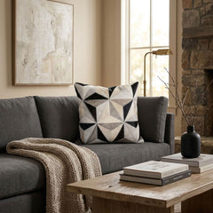 Black and ivory faceted cowhide patchwork cushion styled on a grey sofa in a contemporary living room