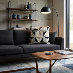 Black and ivory geometric cowhide patchwork cushion on a charcoal sofa in a modern interior