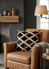 Black and tan cowhide patchwork cushion with lattice design styled on a tan leather armchair