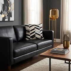 Black and white chevron cowhide cushion styled on a black leather sofa in a contemporary interior