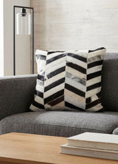 Black and white chevron cowhide patchwork cushion styled on a grey sofa in a modern living room