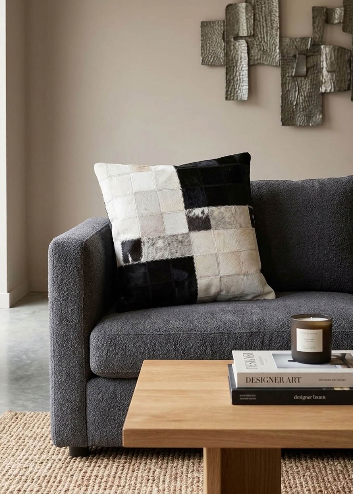 Black and white colour block cowhide patchwork cushion styled on a modern grey sofa