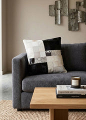 Black and white colour block cowhide patchwork cushion styled on a modern grey sofa