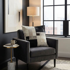Black and white cowhide patchwork cushion on a charcoal grey armchair in a modern interior