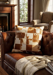 Brown and white checkered cowhide patchwork cushion styled on a brown leather sofa