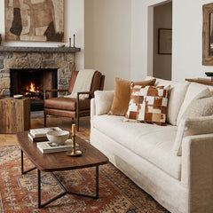 Brown and white cowhide patchwork cushion styled on a neutral sofa in a warm living room