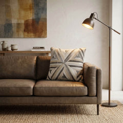 Ivory and grey geometric cowhide patchwork cushion styled on a brown leather sofa in a modern living room