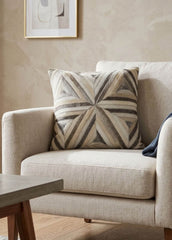 Ivory and grey radiant cowhide cushion styled on a cream armchair in a neutral contemporary interior