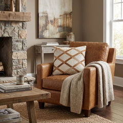 Tan and ivory cowhide patchwork cushion with lattice design styled on a tan leather armchair