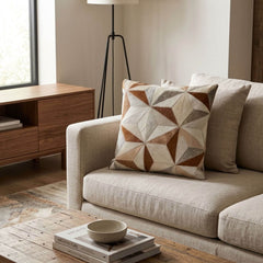 Tan and ivory faceted cowhide cushion styled on a cream sofa in a warm contemporary interior