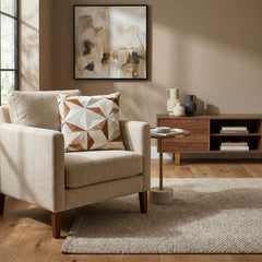Tan and ivory geometric cowhide patchwork cushion on a neutral armchair in a modern living room